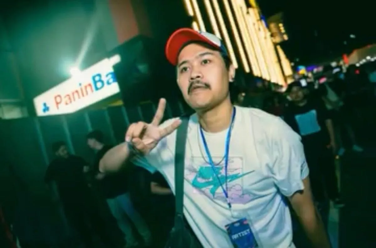 Potret Dwi Sumantri mengenakan topi merah di sebuah acara musik